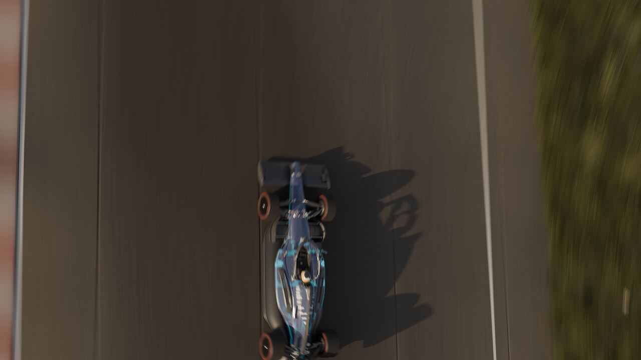 Helicopter view looking down on the car through a corner, kerbs, run-off, grass and treeline filling the frame.